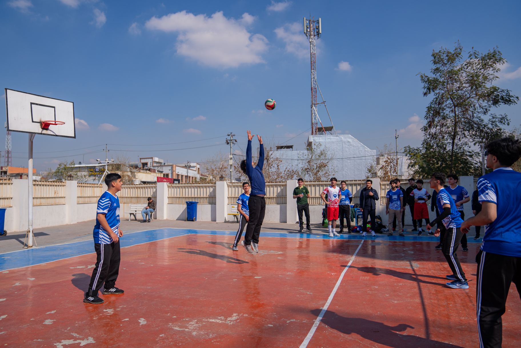 Boys volleyball team playing a match against another school on the compound court