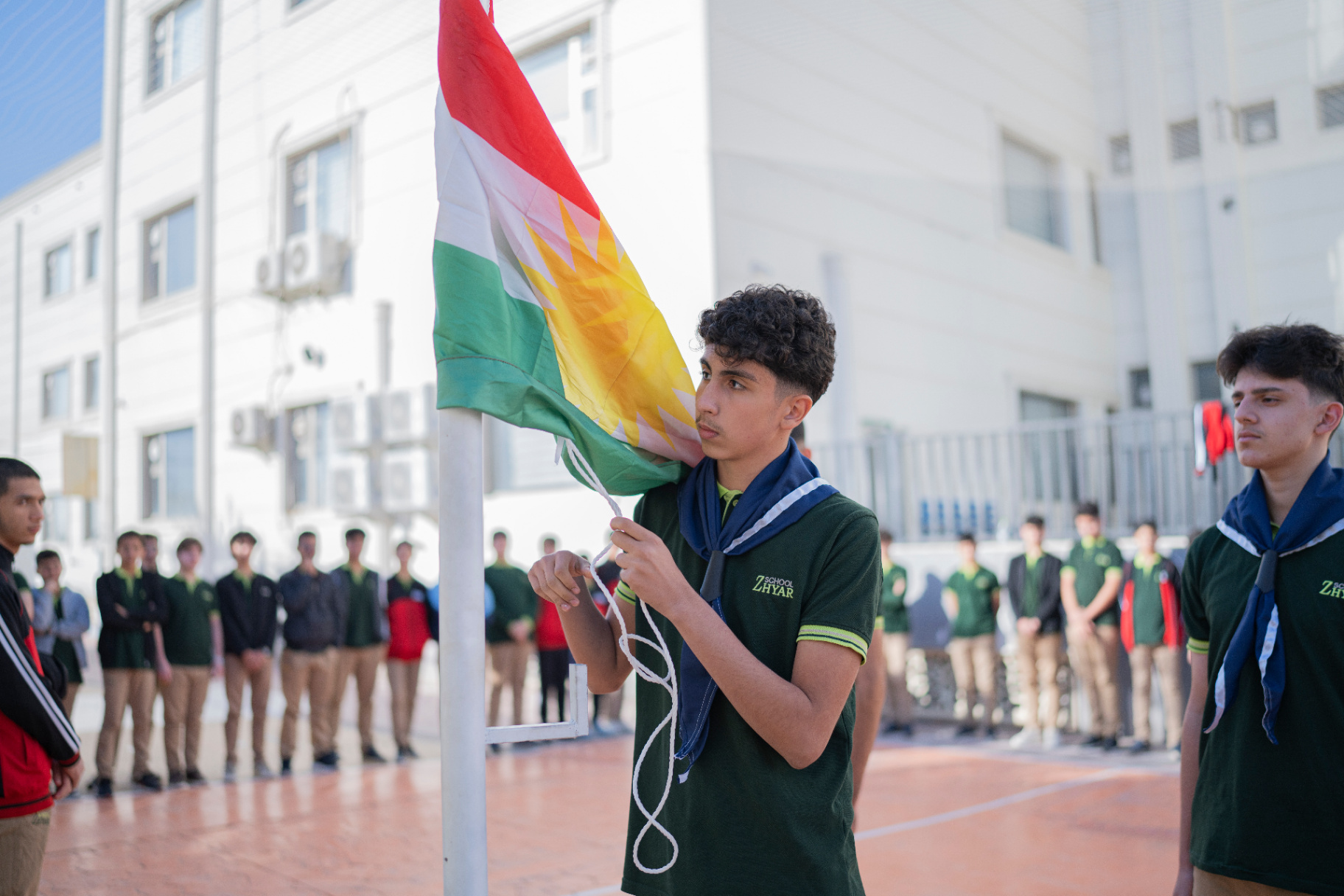 Boys holding the Kurdistan flag during the Kurdish Flag Day celebration at school
