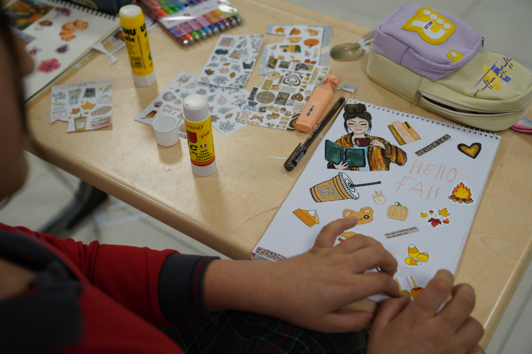Students making autumn-themed posters with paint and coloured paper in class