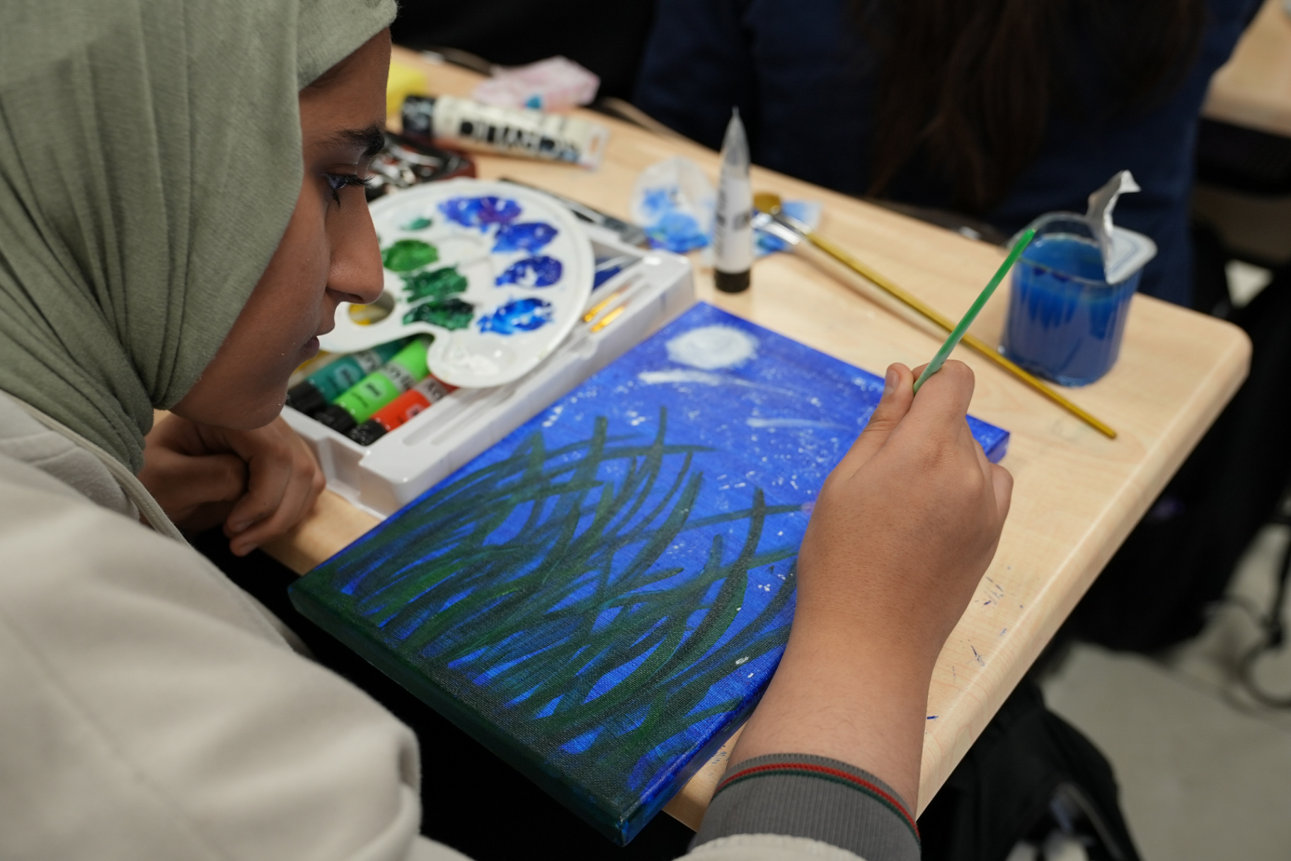 Students painting and drawing at their desks during the school art competition